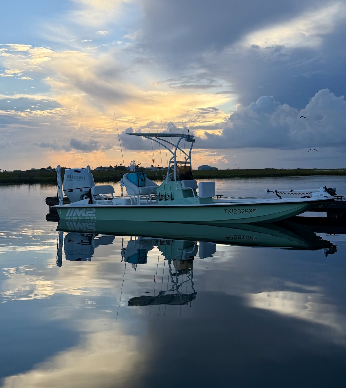 The Majek M2 Illusion tied at the dock at sunrise, mirrored in flat calm water